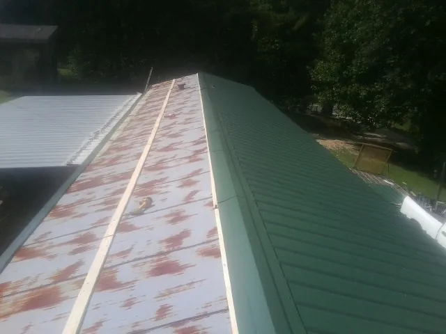 Old rusted panels beside newly installed green metal roofing — Wind Damage Roof Repair by Roofing Brothers in Stanley